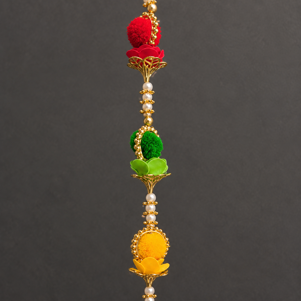 Close-up of red green and yellow pom-poms with floral and bead details