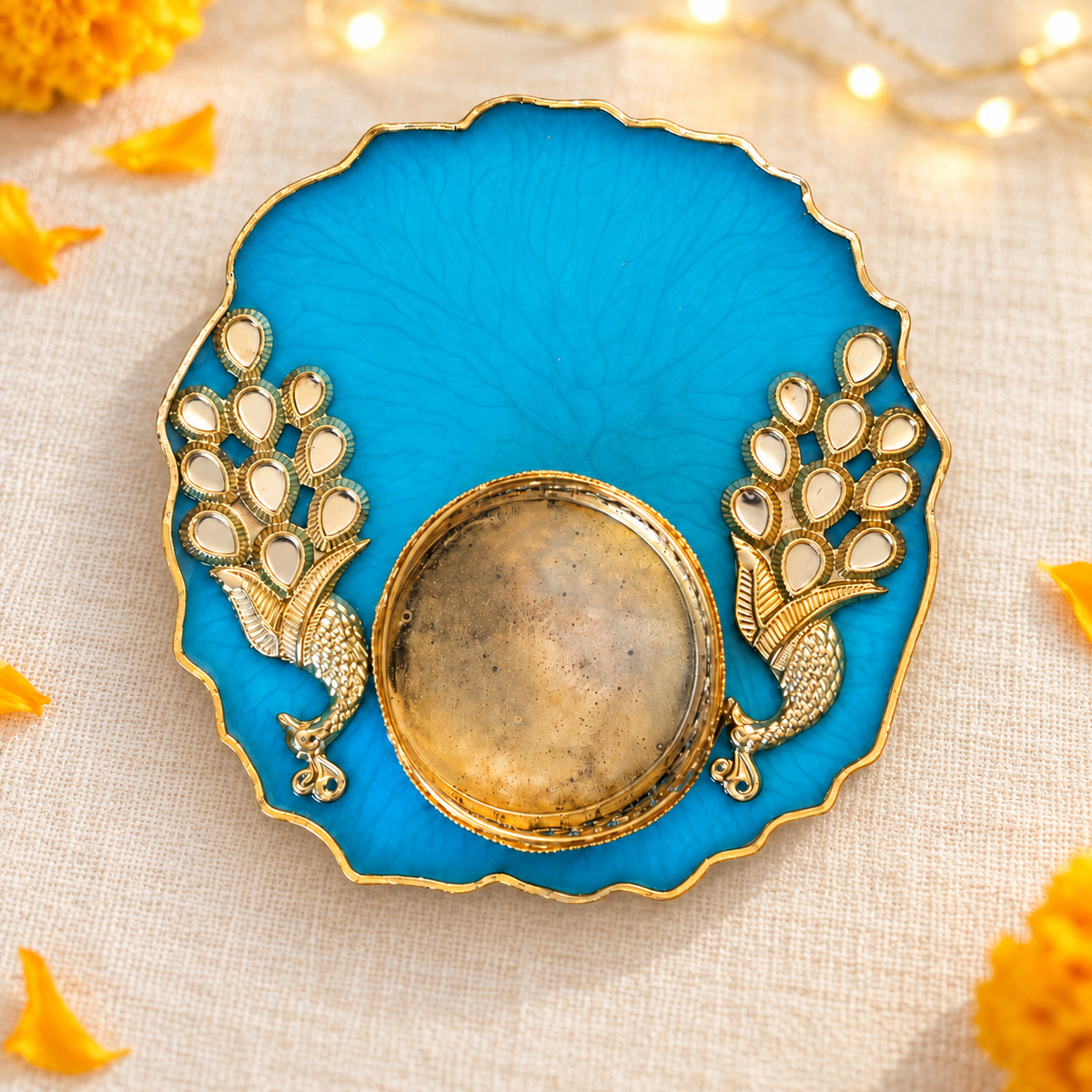 Peacock-blue resin tealight holder on ivory linen with marigold accents and warm decorative lights; props not included