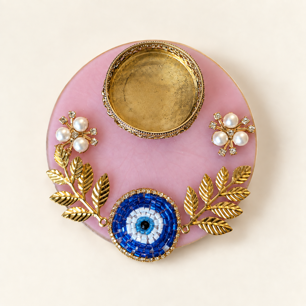 Pink resin tealight holder with blue beaded evil eye, gold-tone leaf accents and pearl-style flowers
