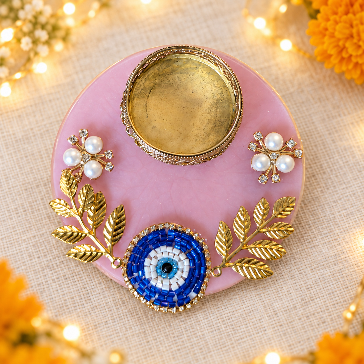 Pink resin tealight holder with blue beaded evil eye, gold-tone leaf accents and pearl-style flowers