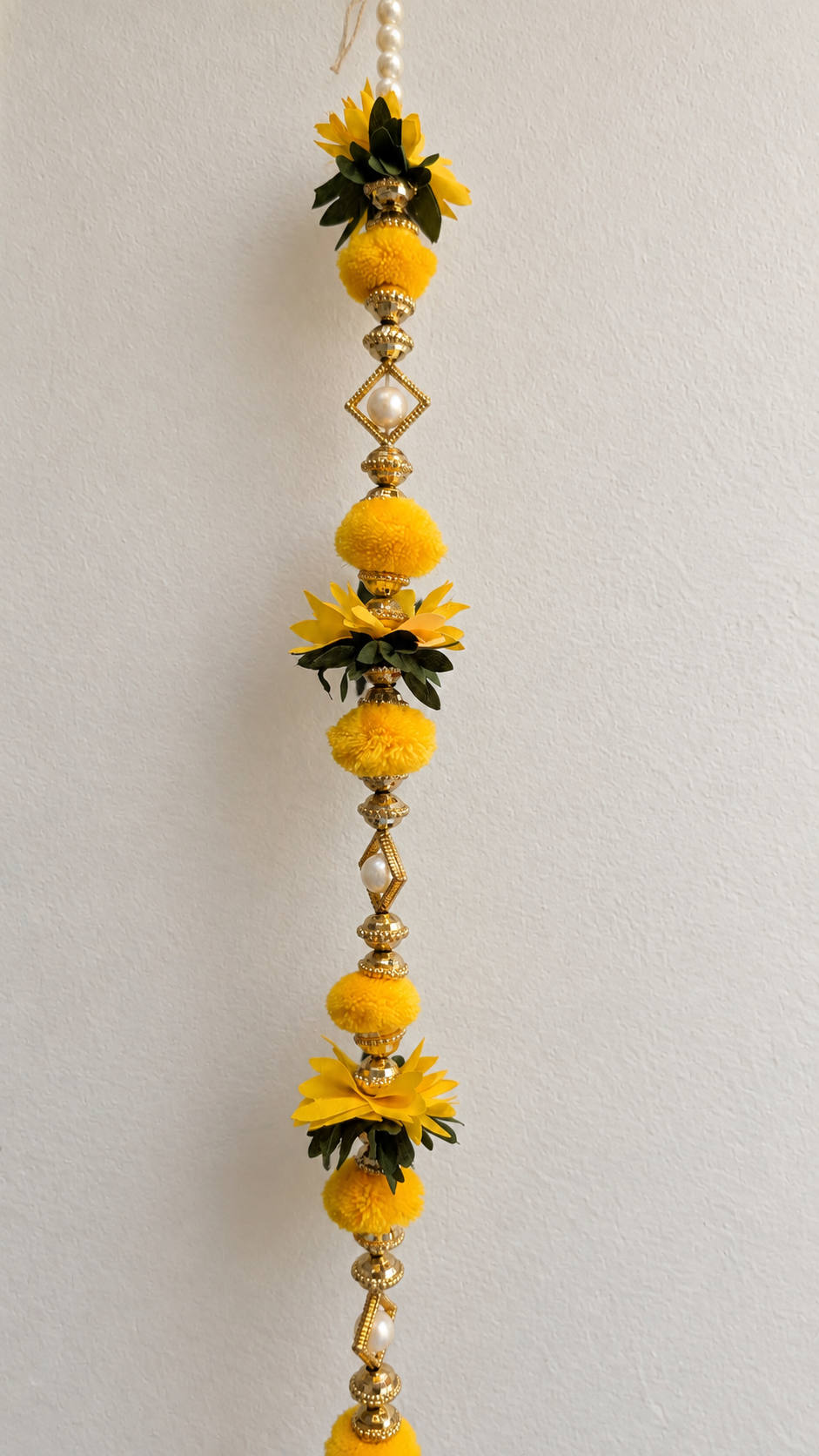 Close-up of yellow pom-poms, flowers and pearl-style beads